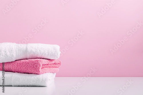 Stack of soft towels on pink background, bathroom