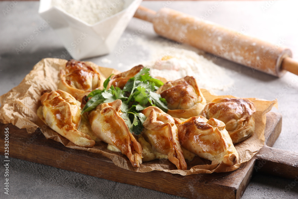 Bakery products. Pies on the board near  a rolling pin, flour on a light background. Background image, copy space
