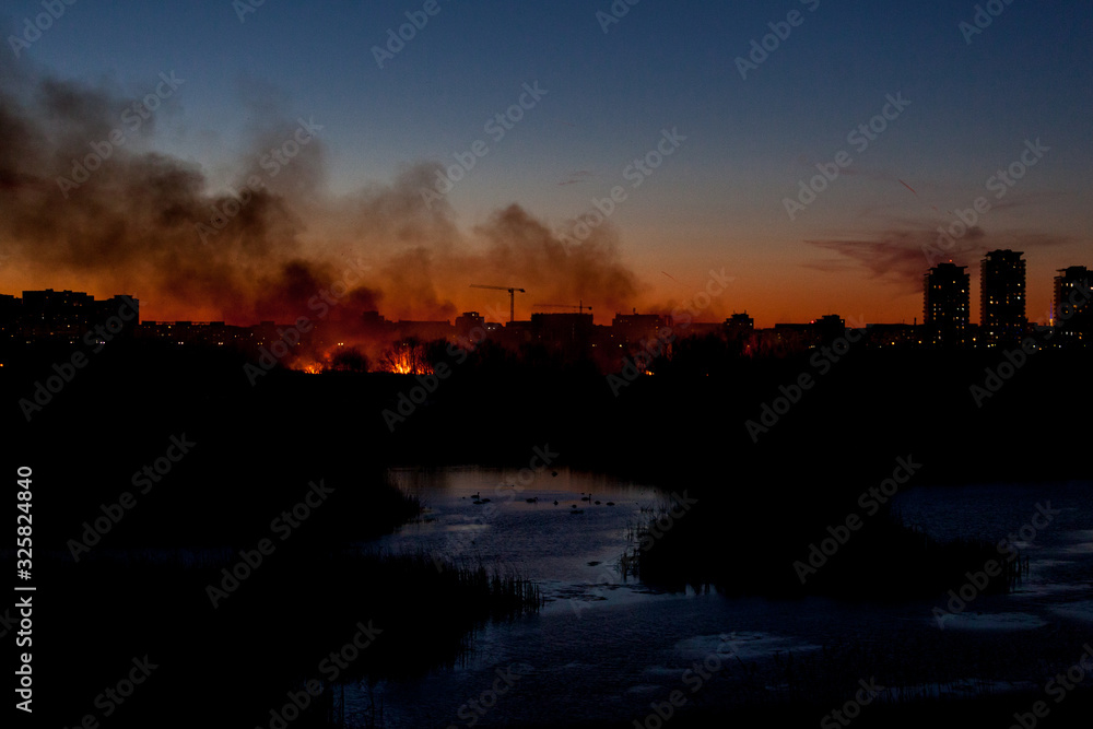 Obraz premium Bucharest, Romania- 02 24 2020: Huge bush fire in Delta Vacaresti- Parcul Natural Vacaresti , over 5 ha of vegetation burned down, fanned by strong winds. People were watching from the distance. 