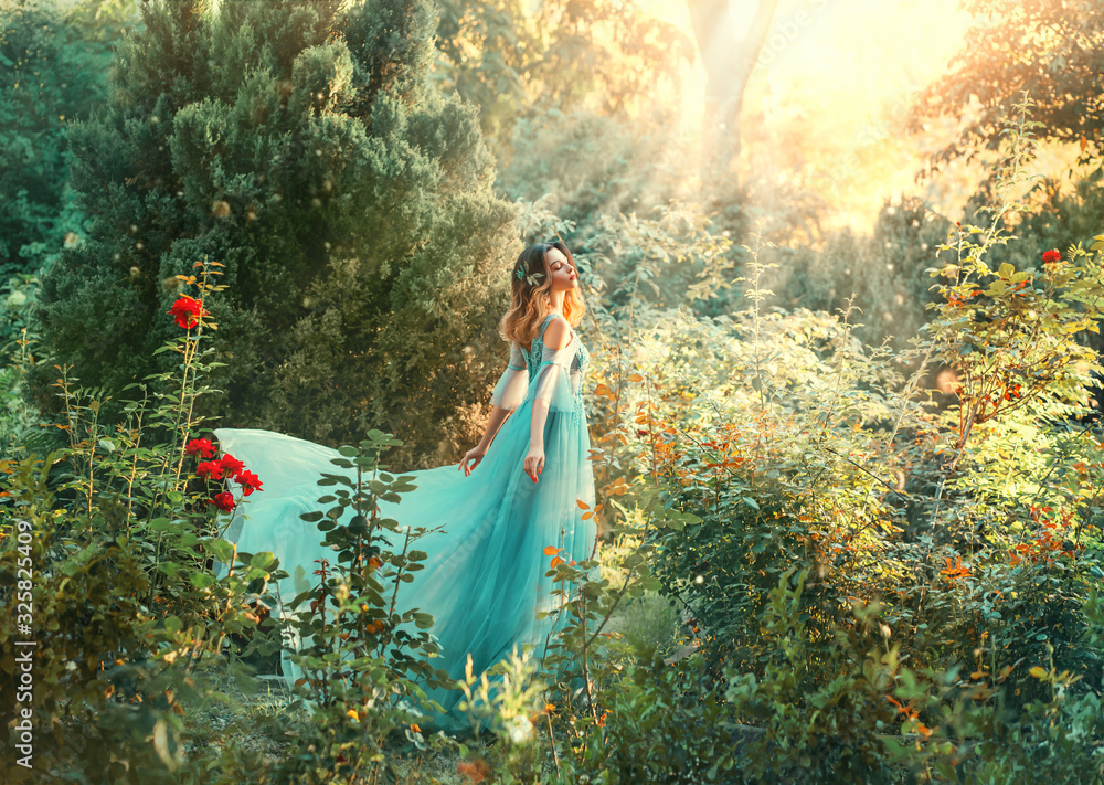 Fotka „Fairytale nymph enjoy bright sun in green forest. Hairstyle  decorated blue flowers flowing hair. Fairy in long blue airy dress train  fly wavy. Backdrop natural tree bushes of red roses divine