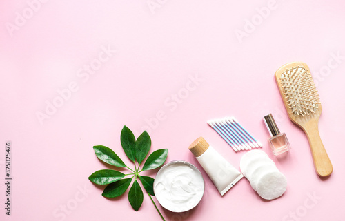  Daily hygiene products with cotton pad, towel, cream and lotion on pink background with top view and space for text