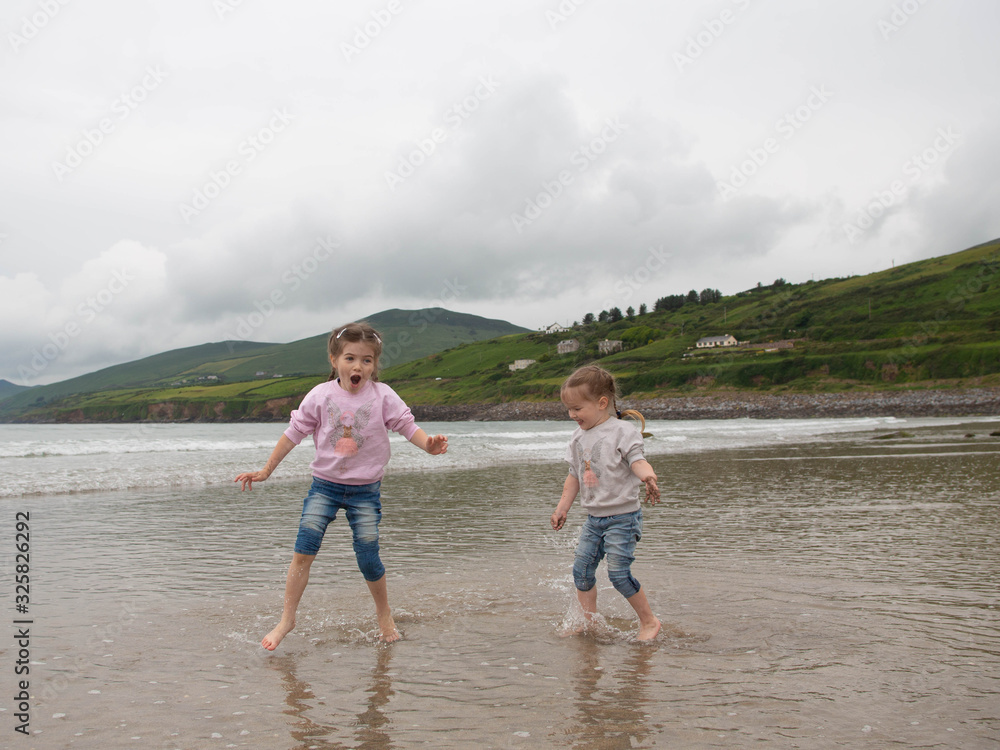 Children play on the coast of the Atlantic Ocean, family holidays in Ireland, Inch Beach, County Kerry Ireland