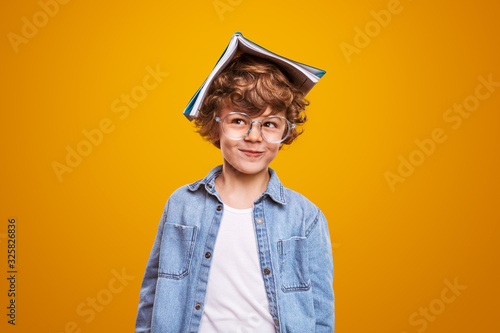 Bild auf Leinwand Curious pupil with textbook on head