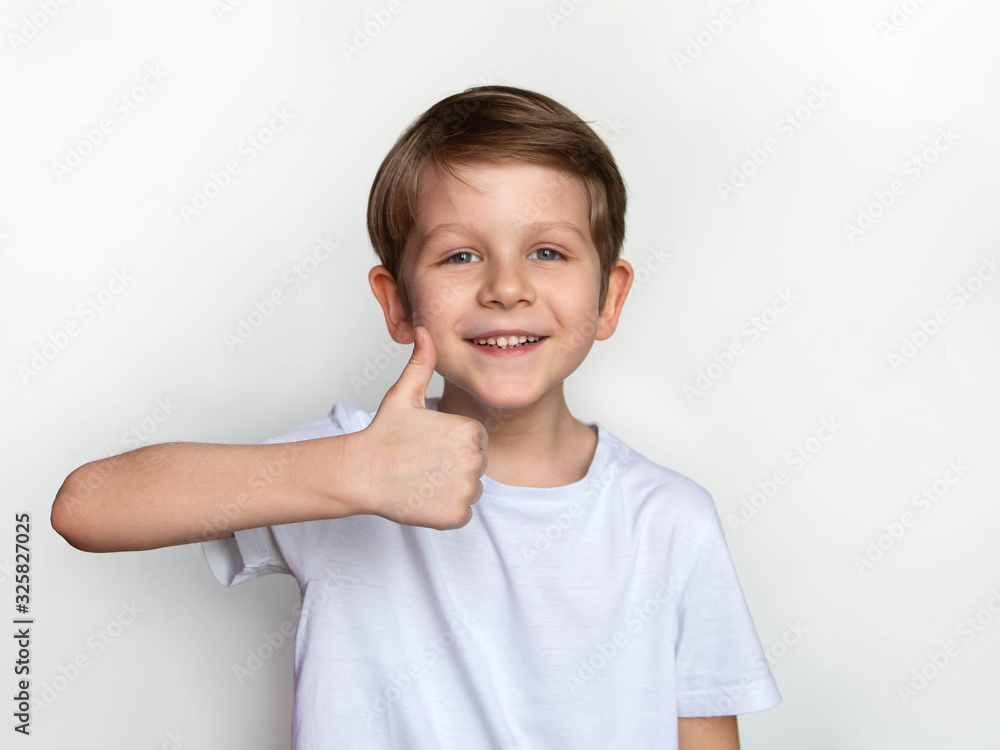 portrait of a little happy boy in blank white T-shirt, showing thumb up, Ok sign, t shirt design concept