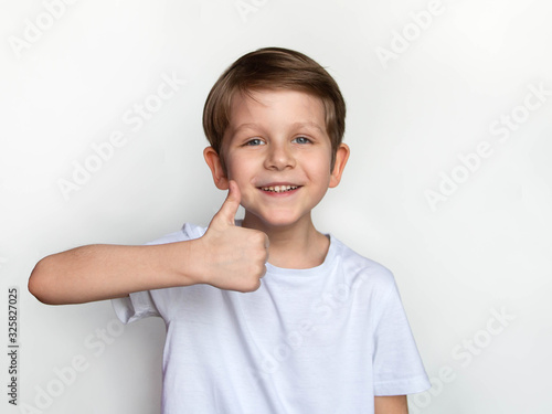 Obraz na płótnie portrait of a little happy boy in blank white T-shirt, showing thumb up, Ok sign, t shirt design concept w salonie