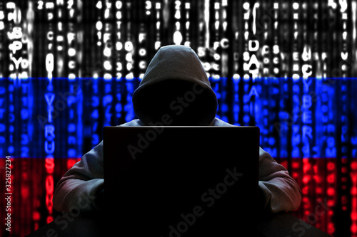 Cyber threat from Russia. Russian hacker at the computer, on a background of binary code, the colors of the flag of Russia. DDoS attack.