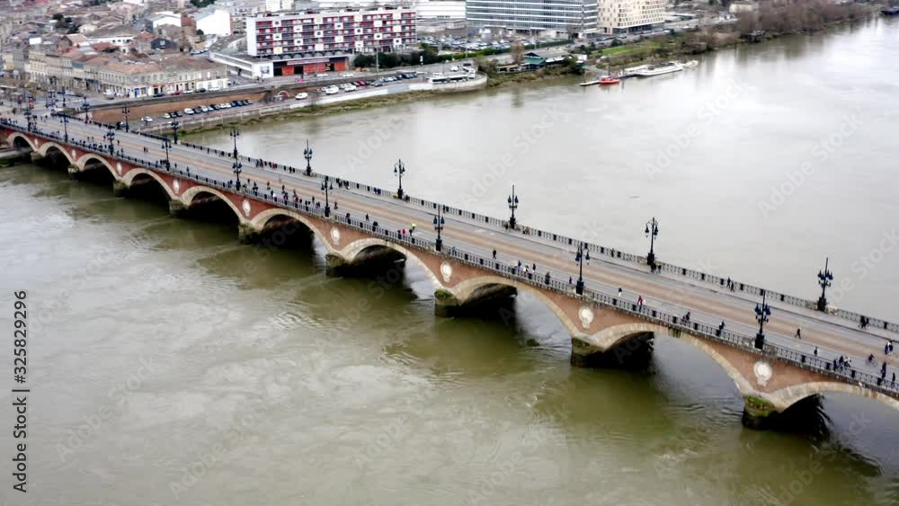 Pont de Pierre pedestrian bridge that crosses the Garonne river in Bordeaux France from the Napoleonic era, Aerial flyover left-pan reveal shot