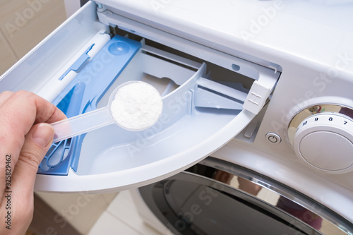 A housewife adding a phosphate-free detergent to a washing machine drawer.