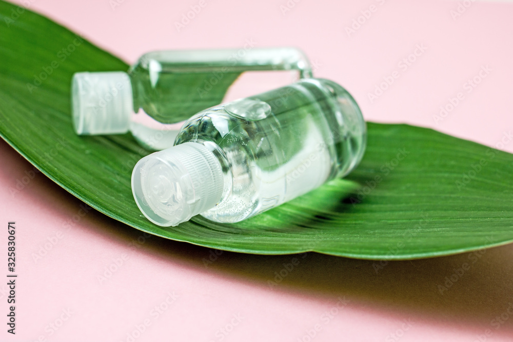 Green cosmetics, body care products.Two transparent cosmetic bottles on a large green leaf of a plant on a pink background, top view, copy space.The concept of organic cosmetics and natural skin care Green cosmetics, body care products.Two transparent cosmetic bottles on a large green leaf of a plant on a pink background, top view, copy space.The concept of organic cosmetics and natural skin care