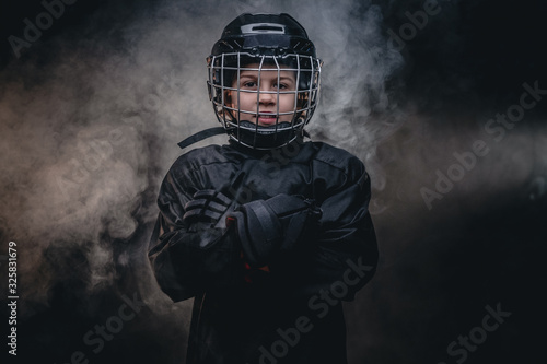 Photography Young blonde sporty boy, ice hockey player, posing in a dark studio for a photos