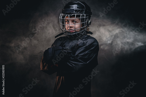 Canvas Print Young blonde sporty boy, ice hockey player, posing in a dark studio for a photos