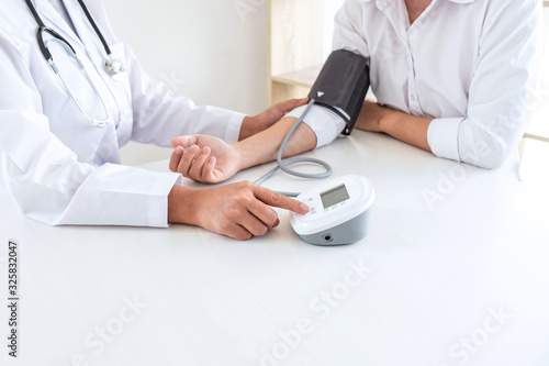 Doctor using Blood pressure monitor and stethoscope checking measuring arterial blood pressure on arm to a patient in the hospital, healthcare and medical concept