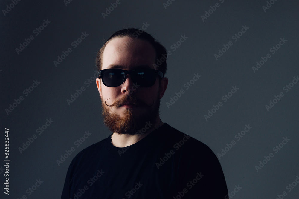 Obraz premium Handsome young man with a beard and mustache in sunglasses in fashionable clothes.