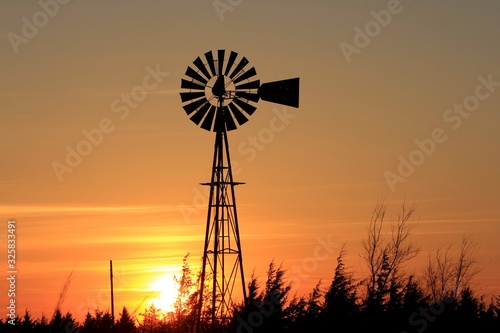 Colorful Kansas Sunset with Sky, and Windmill silhouette west of Nickerson Kansas USA out in the Country. photo