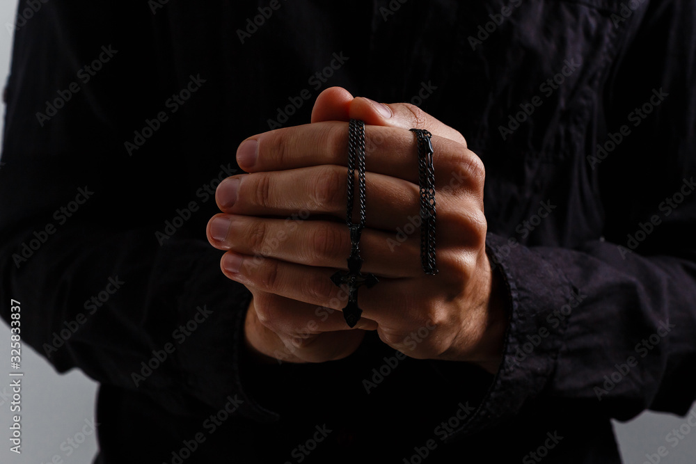 man prays with a cross on a black background