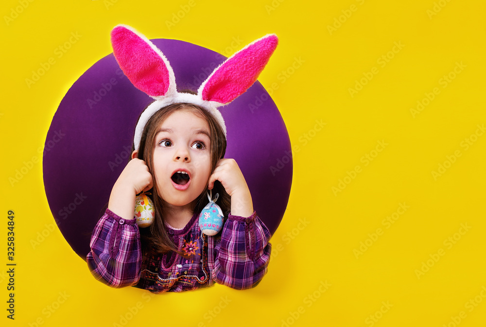 Funny happy child girl with Easter eggs and bunny ears on yellow Funny happy child girl with Easter eggs and bunny ears on yellow