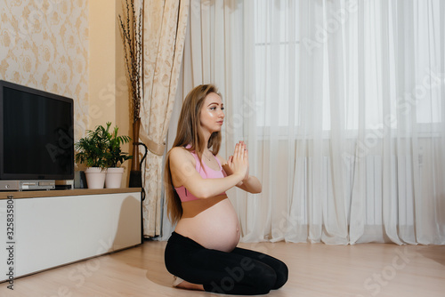 A pregnant girl does yoga at home. Health
