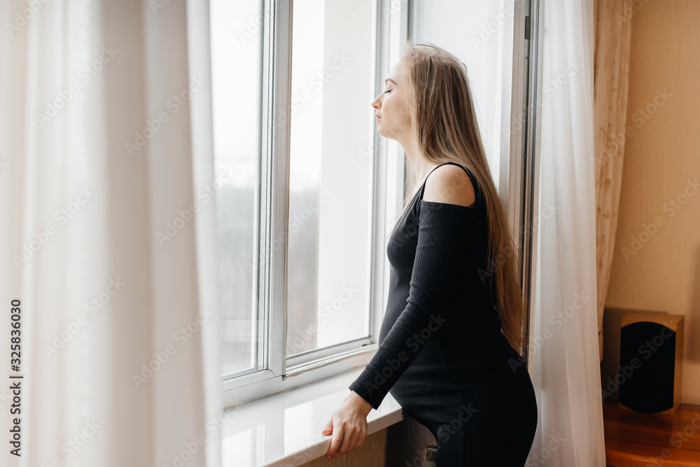 A pregnant girl is breathing fresh air from the window A pregnant girl is breathing fresh air from the window