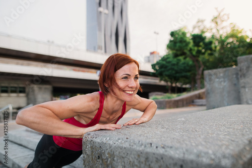 Young woman doing exercise outdoors in city.