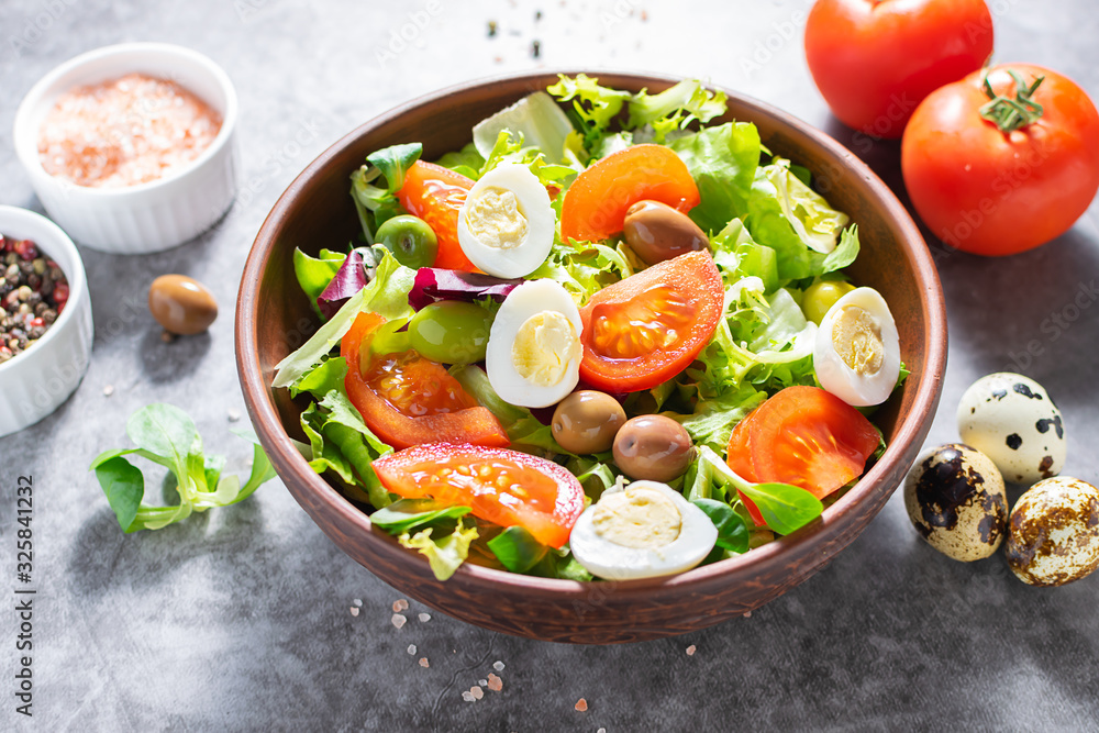 Fresh organic green salad with tomatoes, olives and quail eggs on dark stone table with copy space for your text. Healthy food concept. Fresh organic green salad with tomatoes, olives and quail eggs on dark stone table with copy space for your text. Healthy food concept.