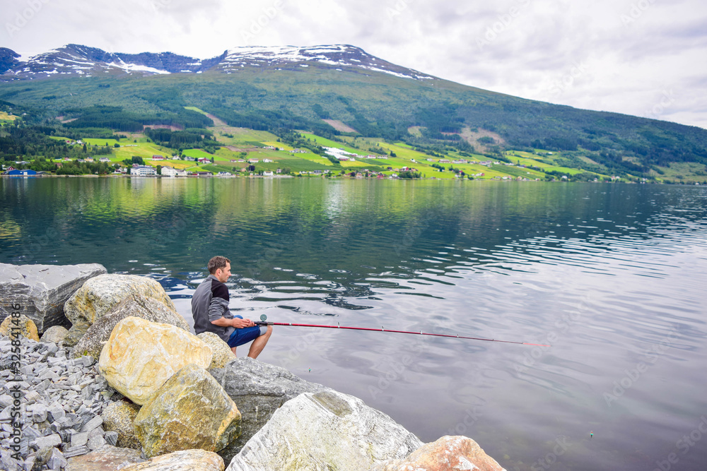 The man is fishing in Innvikfjord. The Innvikfjord is a sub-fjord of Nordfjord in Stryn municipality in Sogn og Fjordane. Norway.
