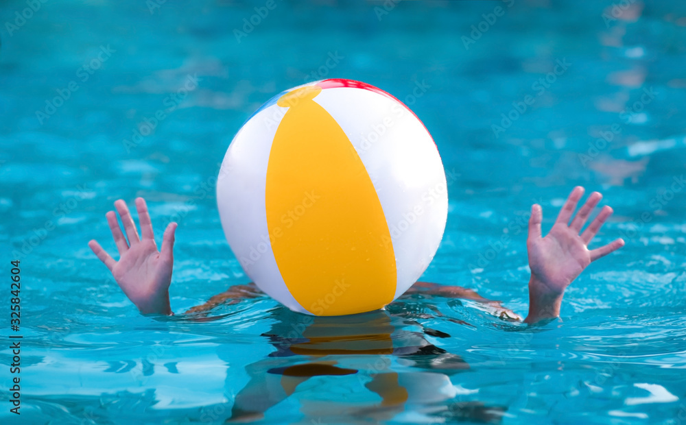 Teenager with a ball on his head in the pool