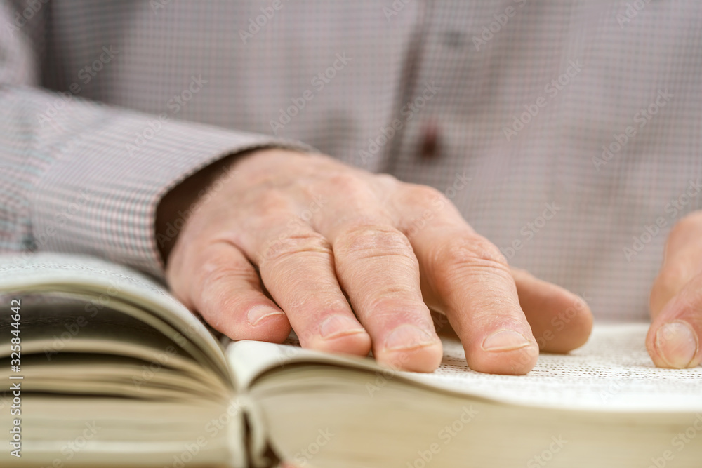 senior man reads interesting book at table in light room senior man reads interesting book at table in light room