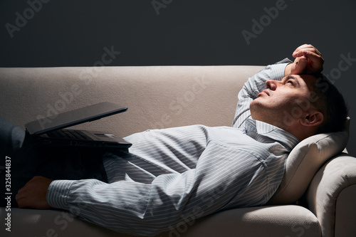 businessman is lying on the sofa with laptop and resting
