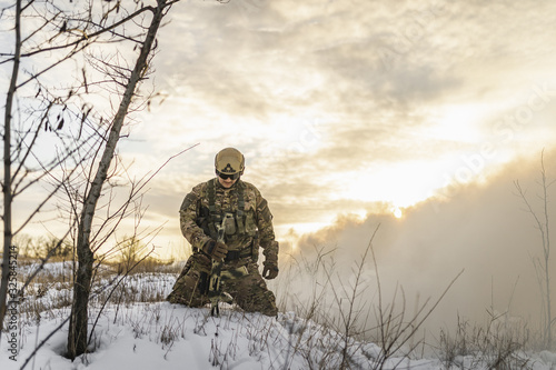 exhausted soldier man after battle fells to knees or kneeling in winter desert. commandos with equipment . Modern warfare battlefield soldier is on his knees and looking to sky