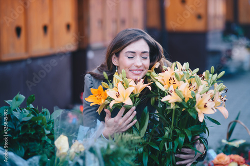 Photography A woman smelling lilies in front of a flower shop on the street