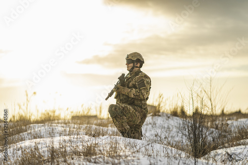 Modern Ukrainian soldier in the winter field patrols the territory from the enemy. War conflict of Russia and Ukraine.