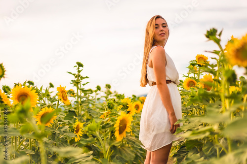 Rural Lifestyle  a young blonde in a field of sunflowers looking to the left