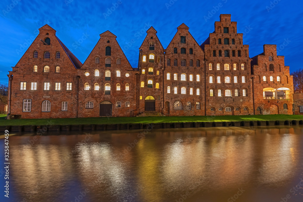 Naklejka premium Historische Salzspeicher in der Altstadt von Lübeck an der Trave bei Nacht. Mit Spiegelung im Wasser.