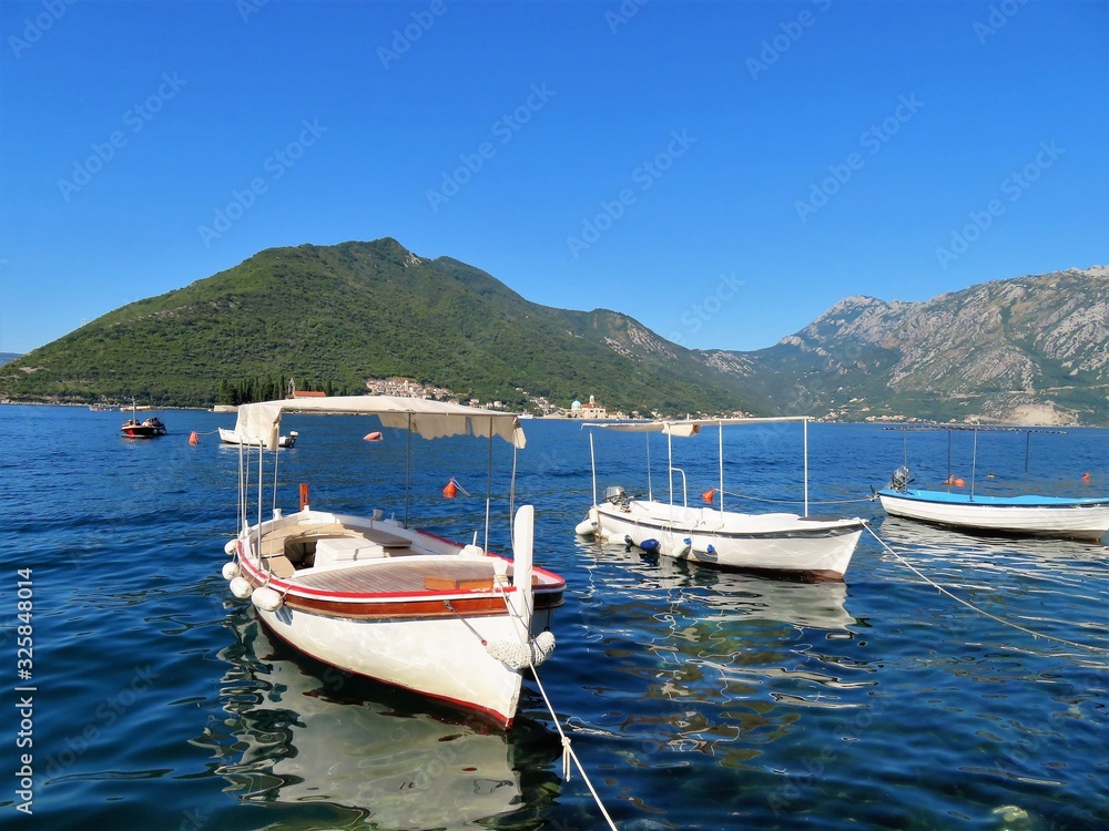 Small boats floating in the water with mountains in the background