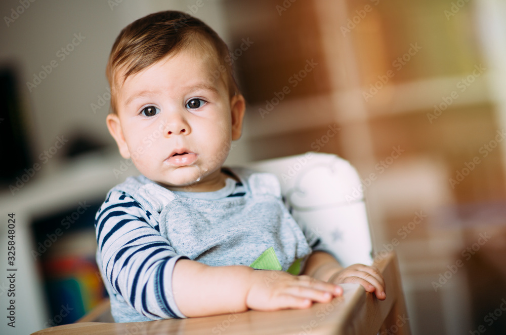 Adorable baby boy sitting in high chair after or before meal. Adorable baby boy sitting in high chair after or before meal.