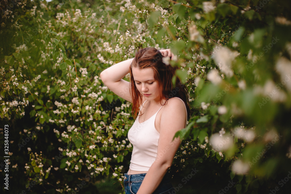 Young woman standing amidst flowering branches in park during spring Young woman standing amidst flowering branches in park during spring