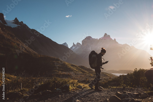Backpacker walking looking at mobile phone in mountains in sunny day