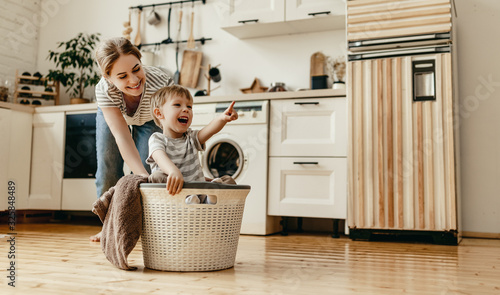 Happy family mother housewife and child   in laundry with washing machine photo