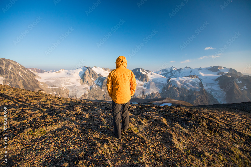Rear view of hiker walking on mountain summit in yellow jacket. Rear view of hiker walking on mountain summit in yellow jacket.