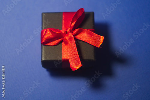 Black gift box flat lay on classic blue background. Holidays concept. Happy new year