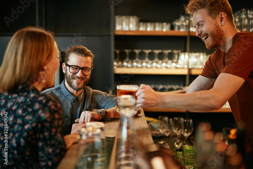 Bartender serving beer to customers. Pub interior.