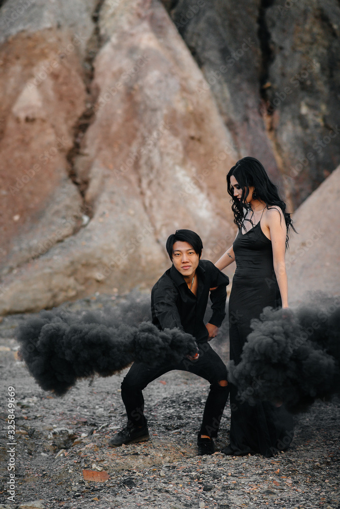 Obraz Zakochana para Azjatów zapaliła czarne bomby dymne w górach. Kolorowy dym