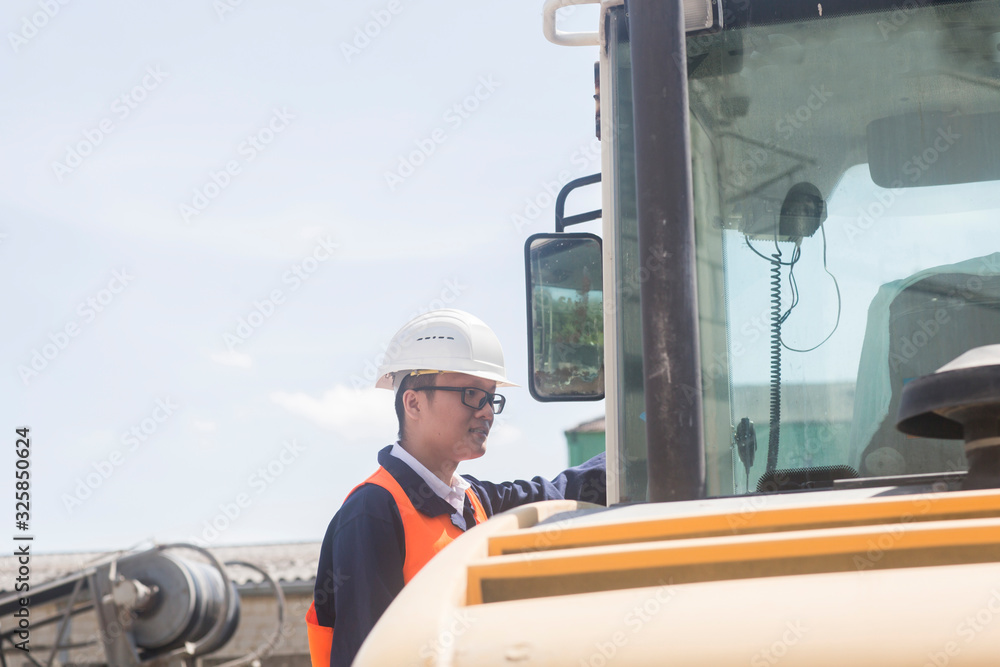 worker standing near an excavator and looking worker standing near an excavator and looking