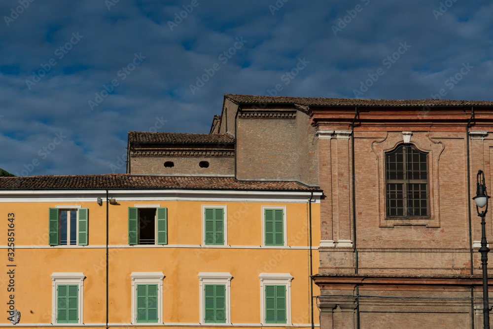 yellow building with green shutters on main sqaure Piazza della Liberta in Bagnacavallo, Italy