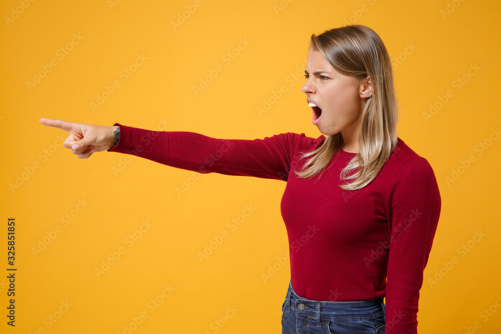 Side view of nervous young blonde woman girl in casual clothes posing isolated on yellow orange background in studio. People lifestyle concept. Mock up copy space. Point index finger aside, swearing. Side view of nervous young blonde woman girl in casual clothes posing isolated on yellow orange background in studio. People lifestyle concept. Mock up copy space. Point index finger aside, swearing.