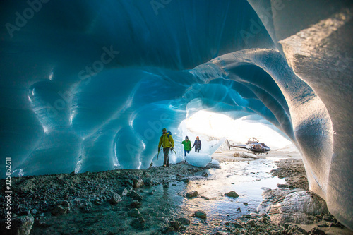 Three ice climbers enter a glacial cave. photo