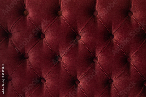 Quilted velour buttoned burgundy red color fabric wall pattern background. Elegant vintage luxury sofa upholstery. Interior plush backdrop