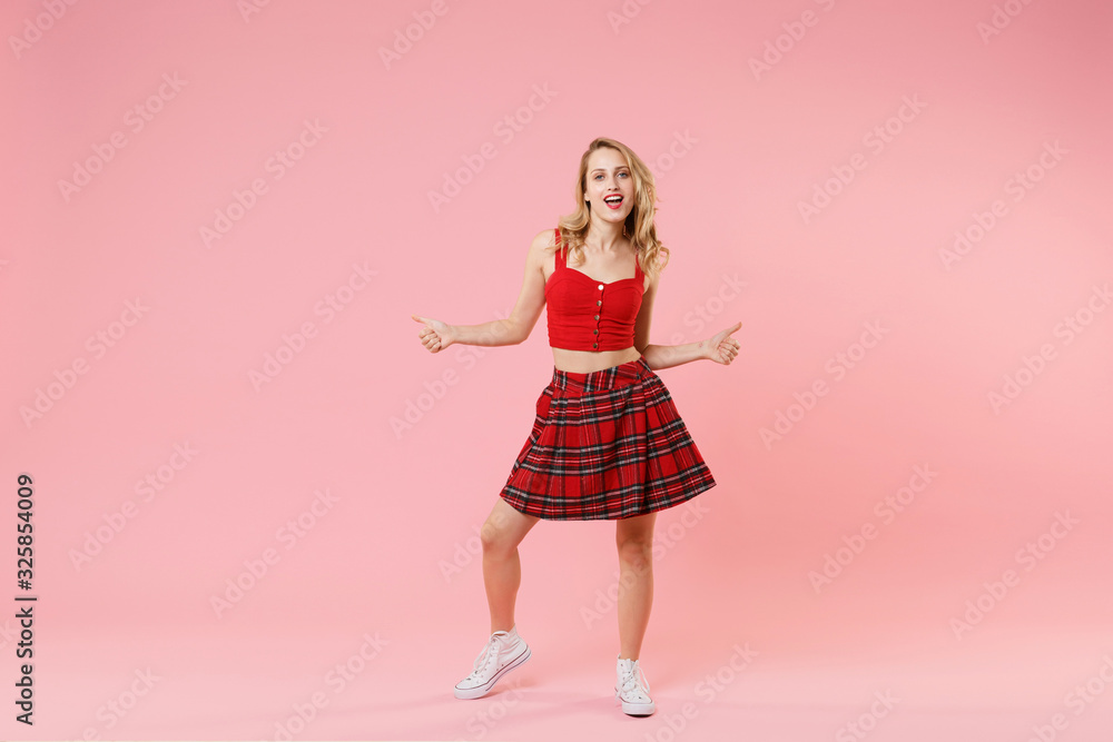 Cheerful young blonde woman girl in red sexy clothes posing isolated on pastel pink wall background studio portrait. People sincere emotions lifestyle concept. Mock up copy space. Showing thumbs up. Cheerful young blonde woman girl in red sexy clothes posing isolated on pastel pink wall background studio portrait. People sincere emotions lifestyle concept. Mock up copy space. Showing thumbs up.