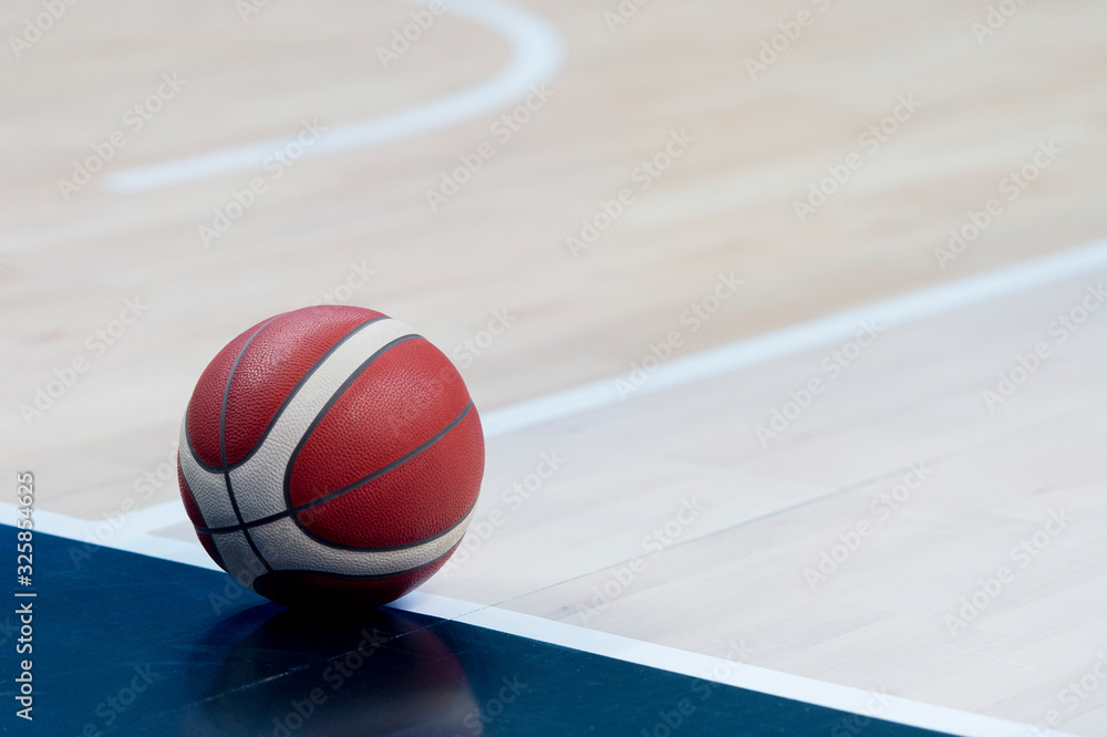 An official orange ball on a hardwood basketball court