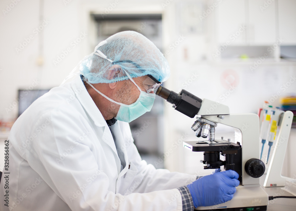 Biologist looking through microscope in laboratory Biologist looking through microscope in laboratory